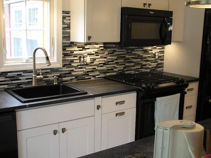 Modern kitchen renovation with black countertops and white cabinets