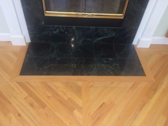 Dark green custom tile hearth and wood flooring